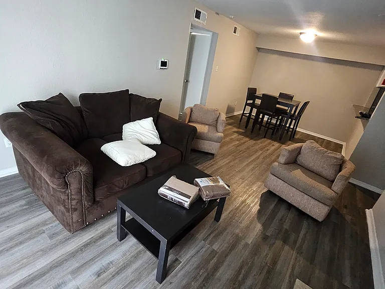 Open living area with plank-style flooring, comfortable seating, and a dining nook that's great for shared meals.