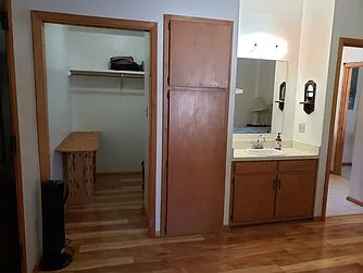 Upstairs front bedroom walk-in closet, cabinet above water heater closet and below bedroom sink, door to bathroom.