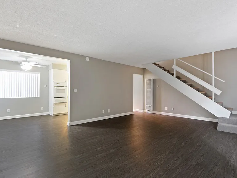 Living room, wood inspired floors throughout the first floor, dining area with ceiling fan on the left