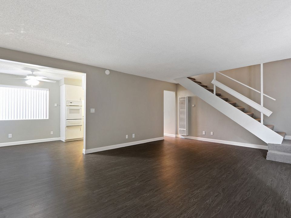 Living room, wood inspired floors throughout the first floor, dining area with ceiling fan on the left