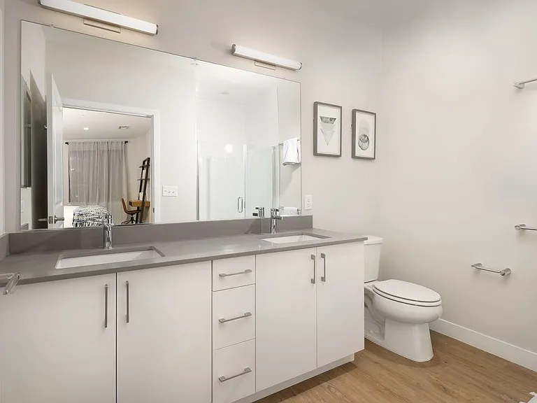 Bath with grey quartz countertop, white cabinetry, and hard surface flooring