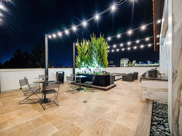 Rooftop terrace with fire pit, string lights, and lounge seating