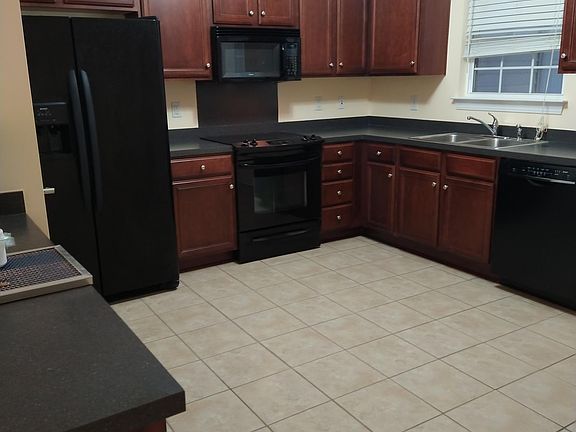 Large Kitchen with tile floor and black appliances.