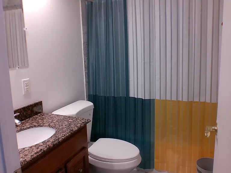 Full bathroom with granite-top vanity, ample under-sink storage, and a tub/shower combo with tile surround.