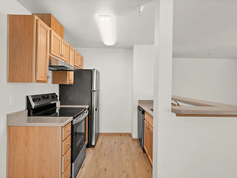 Modern kitchen with stainless steel appliances, light wooden cabinets, and laminate flooring, perfect for culinary enthusiasts. Modern kitchen with stainless steel appliances, light wooden cabinets, and laminate flooring, perfect for culinary enthusiasts.