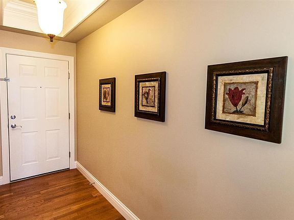 Entrance to unit #401. Foyer has hardwood flooring, decorative crown molding above foyer light and neutral painted interior.