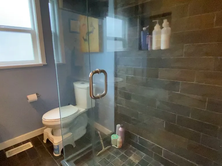 Glass enclosed shower with slate tile.