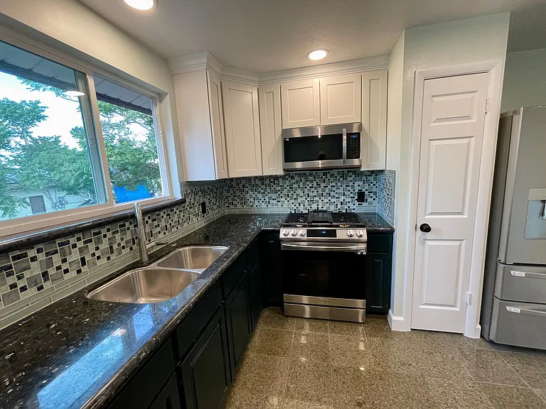 Absolute Granite countertop with glass tile backsplash. Full height cabinets and pantry with custom shelving.