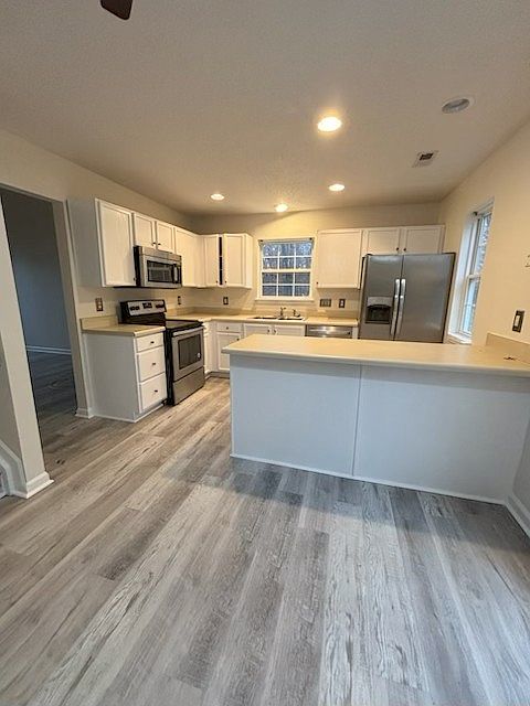 Kitchen with freshly pained white cabinets, stainless steel appliances, and eat-in kitchen area