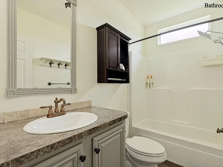 Full bathroom with tub/shower combo, large vanity counter, framed mirror, and extra wall cabinet for storage.