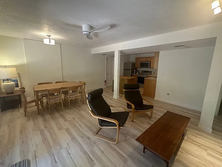 Living room with table and 6 chairs, coffee table, 2 ikea poang chairs and leather coach. Kitchen island. New ceiling fan and paint and new luxury vinyl flooring throughout unit.