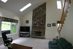 Wall To Ceiling Stone Fireplace with Second Set of Stairs Leading Upstairs 
