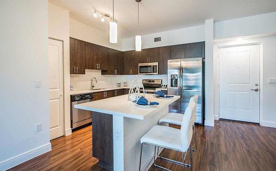 Kitchens feature European espresso custom cabinets with quartz countertops, stainless steel appliances, white tile backsplash, and hard surface flooring