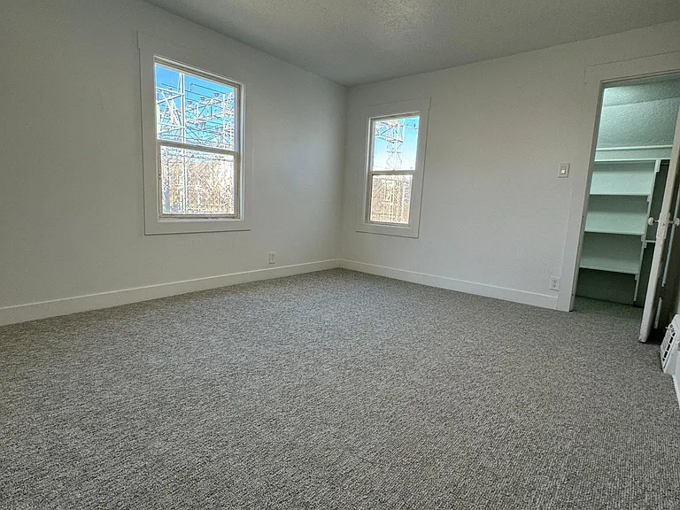 Spacious primary bedroom with plush carpeting and a large walk-in closet.