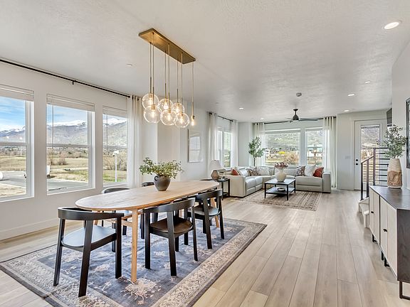 Bright open-concept dining and living room with large windows, mountain views, a wooden dining table