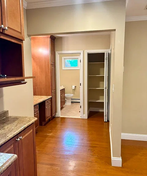 View from kitchen through hallway past desk/vanity area into bathroom. Roomy linen closet.