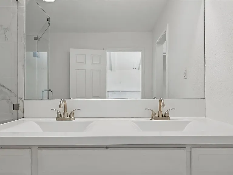 Full bath with double vanity and a shower with shower door
