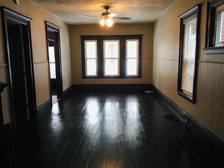 Living room with re-finished original hardwood floors, new fan and light fixture and new windows.