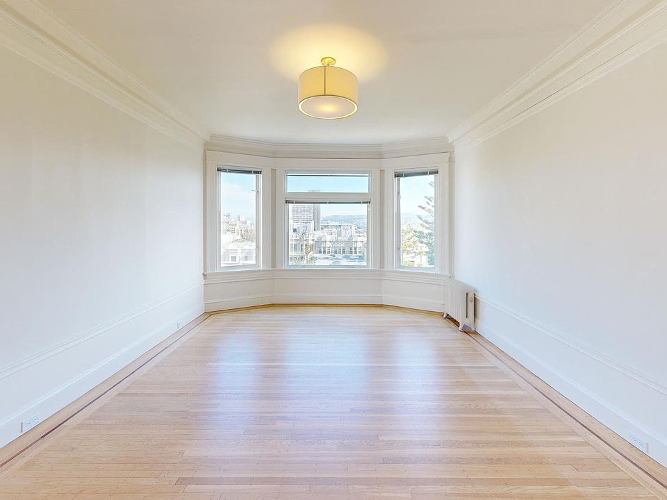 Sunlit room with a large window and wood-like flooring