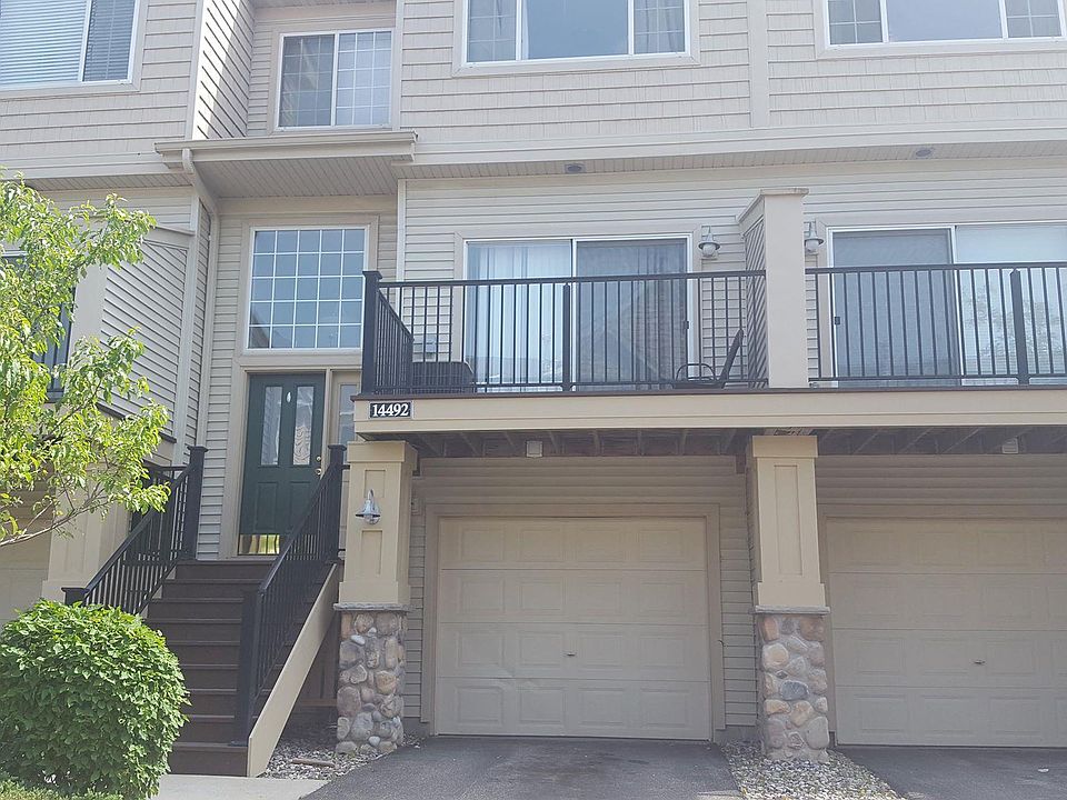 Exterior showing tuck-under garage and balcony above.