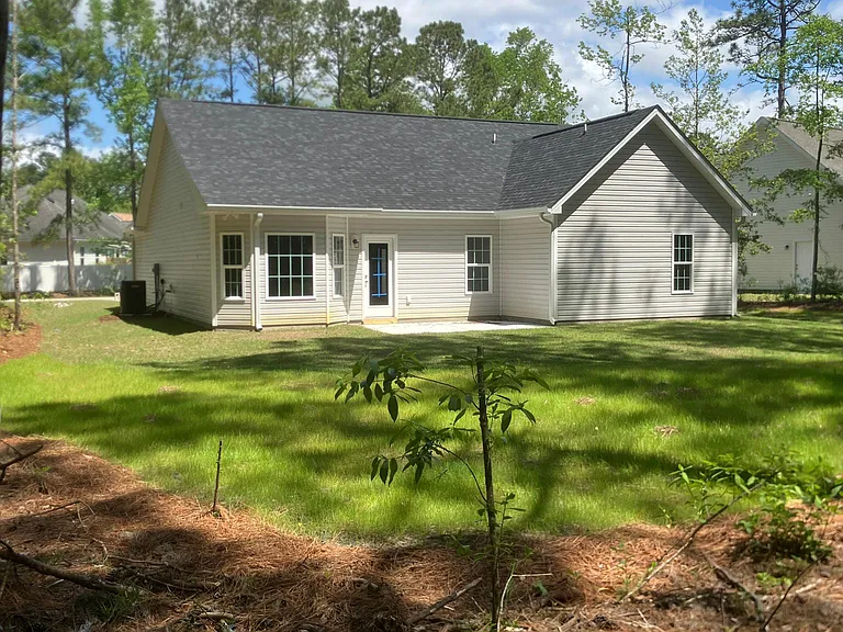 rear of house looking from wooded area in back yard. Living Room opens out onto a 10x14 concrete patio.