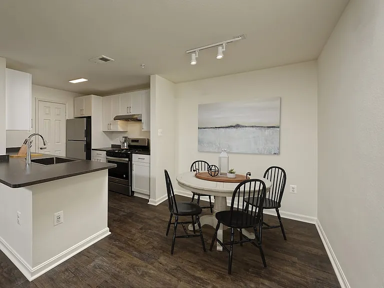 Renovated Package II kitchen and dining area with white cabinetry, dark grey laminate countertops, and stainless steel appliances, and hard surface flooring