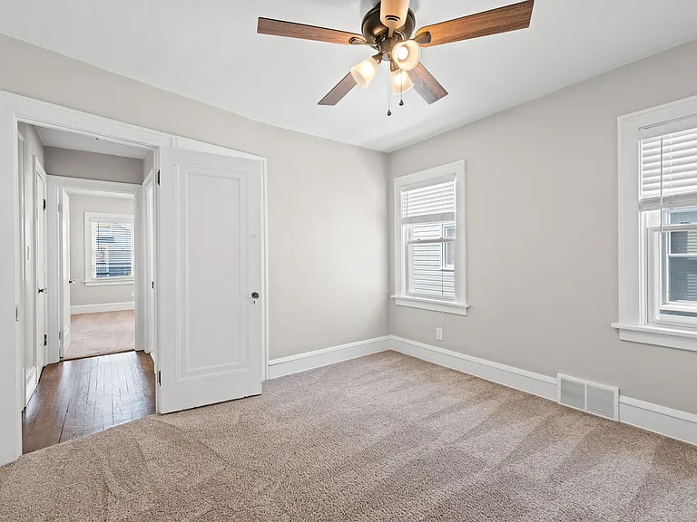 This photo shows the second bedroom on the second/main floor of the unit. It also shows the hallway that leads to the bathroom and other bedroom.