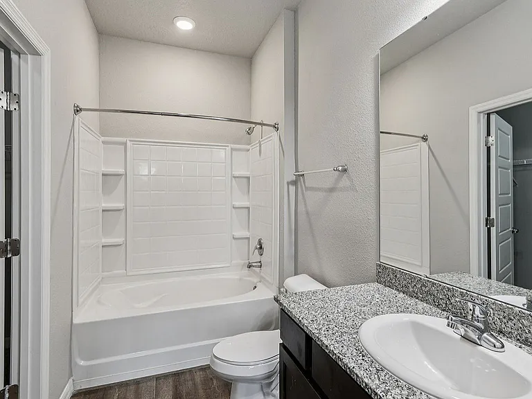 Modern bathroom featuring a sleek granite countertop, spacious bathtub, and elegant fixtures, perfect for relaxation.