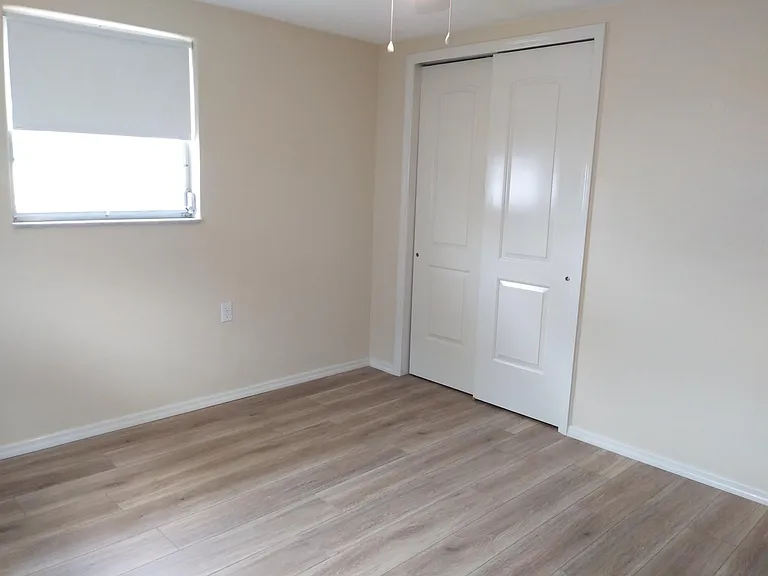 Spare bedroom with new flooring and closet doors.
