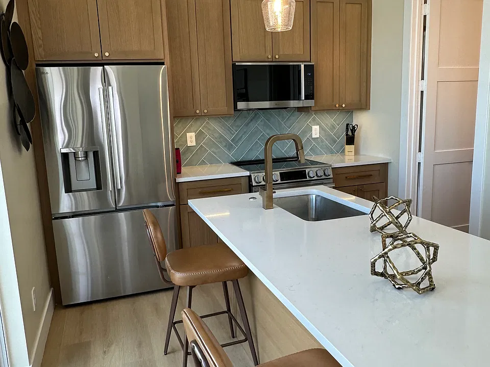 Modern kitchen with stainless steel appliances and breakfast bar seating.
