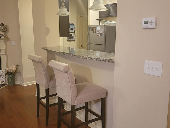 Breakfast Bar with Granite countertop and Pendant lights with view into Galley Kitchen