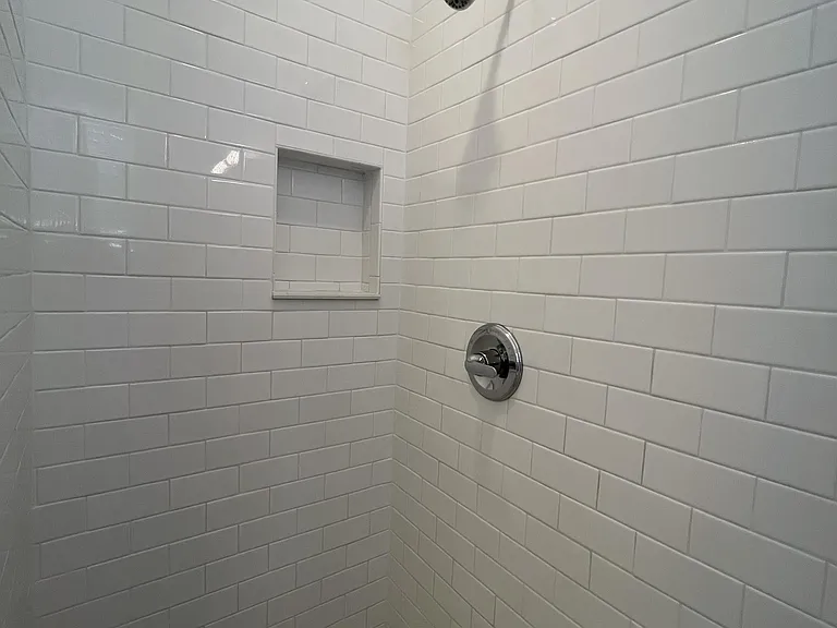 White subway tile shower, with product niche and penny tile floor.