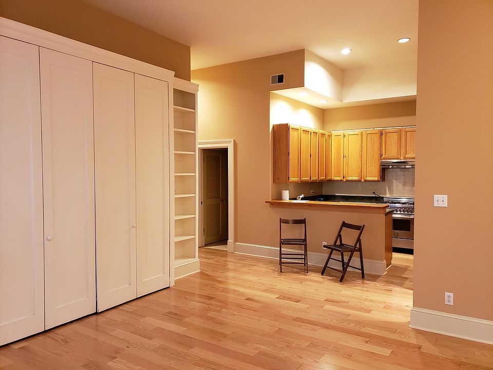 Custom bookshelves and desk area with doors and view of kitchen.