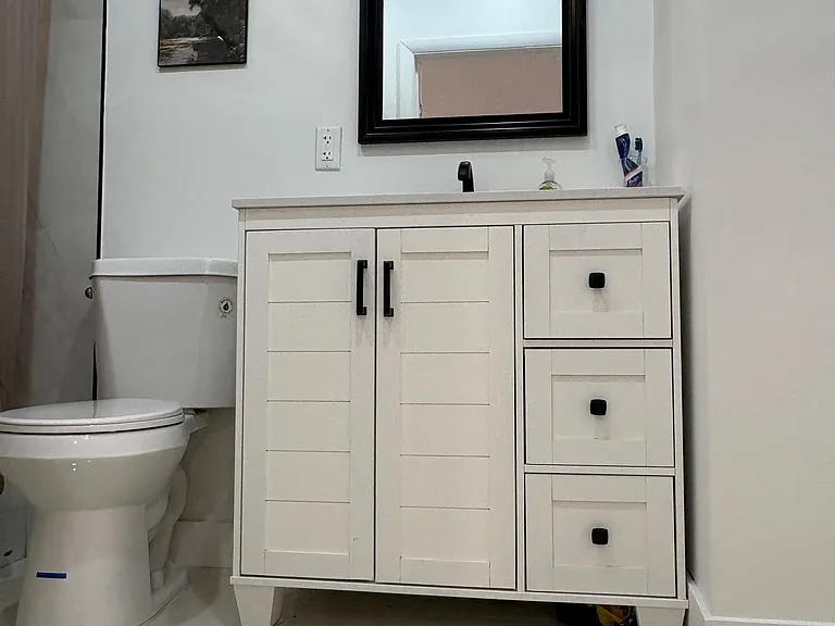 Bathroom features a single-sink vanity with ample cabinet storage, a large framed mirror, and a tub/shower combo.