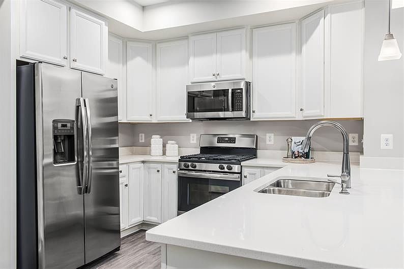 Sleek and sophisticated, the kitchen boasts stunning quartz countertops, premium stainless steel appliances, a stylish subway tile backsplash, and an open layout perfect for cooking and entertaining.