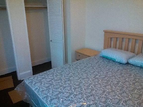 Bedroom with queen bed, dresser, mirror, and night stand.