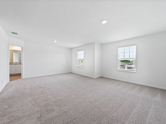 Expansive master bedroom with windows that create a bright, open space.