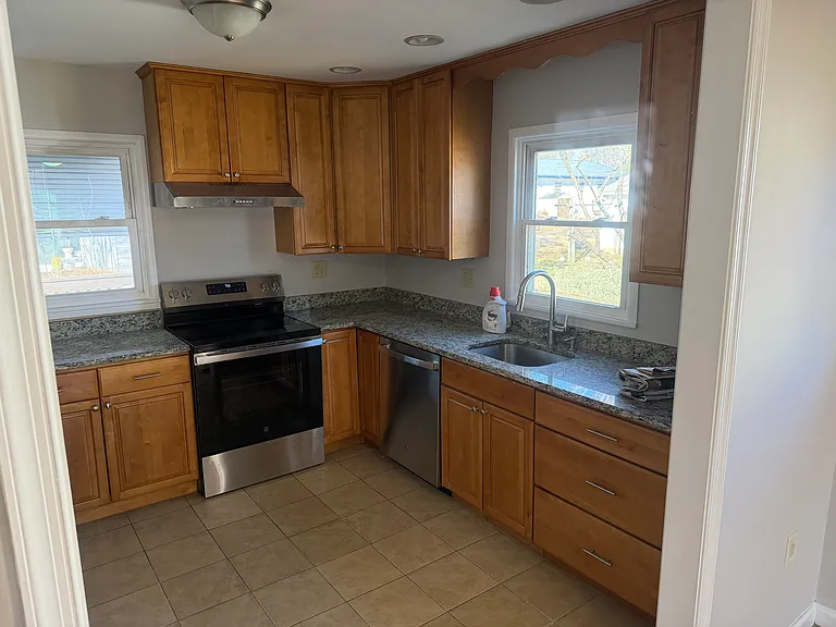 Kitchen with granite counter tops, brand new range, exhaust hood, dishwasher, and sink faucet.