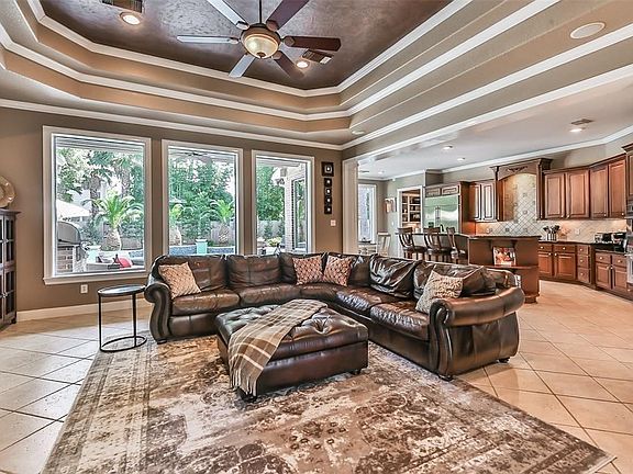 Large great room features double tray ceilings and wall of windows overlooking the summer kitchen and backyard oasis.