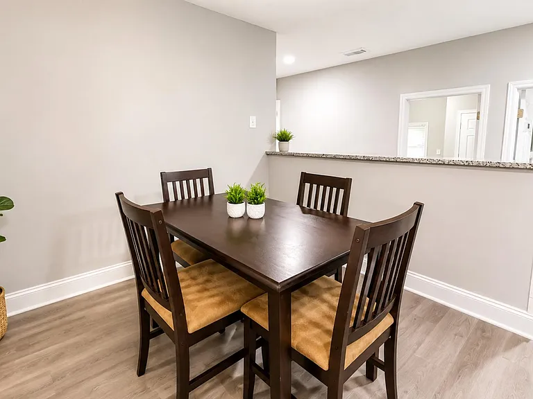 Dedicated dining area with a four-seat table, durable flooring, and a pass-through counter to the kitchen for easy serving.
