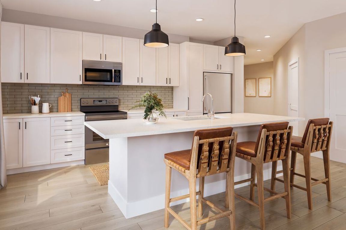 Kitchen with white cabinetry, tile backsplash, stainless steel appliances, pendant lighting, and hard-surface vinyl plank flooring (Rendering)