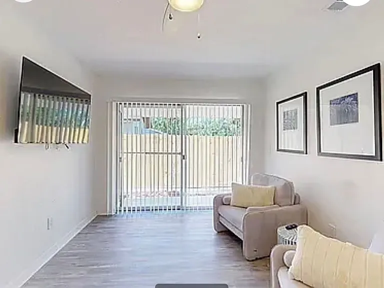 Stylish shared lounge area with two accent chairs, ceiling fan, and framed artwork perfect for relaxing