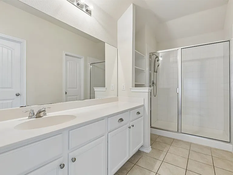 Bathroom featuring an extended vanity with dual sinks, white cabinetry, and brushed nickel hardware