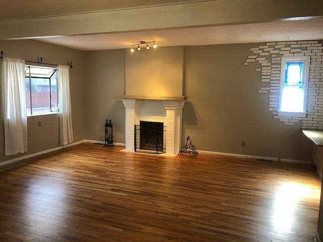 Beautiful, large, open living room with wood burning fireplace and lots of natural light from the windows.