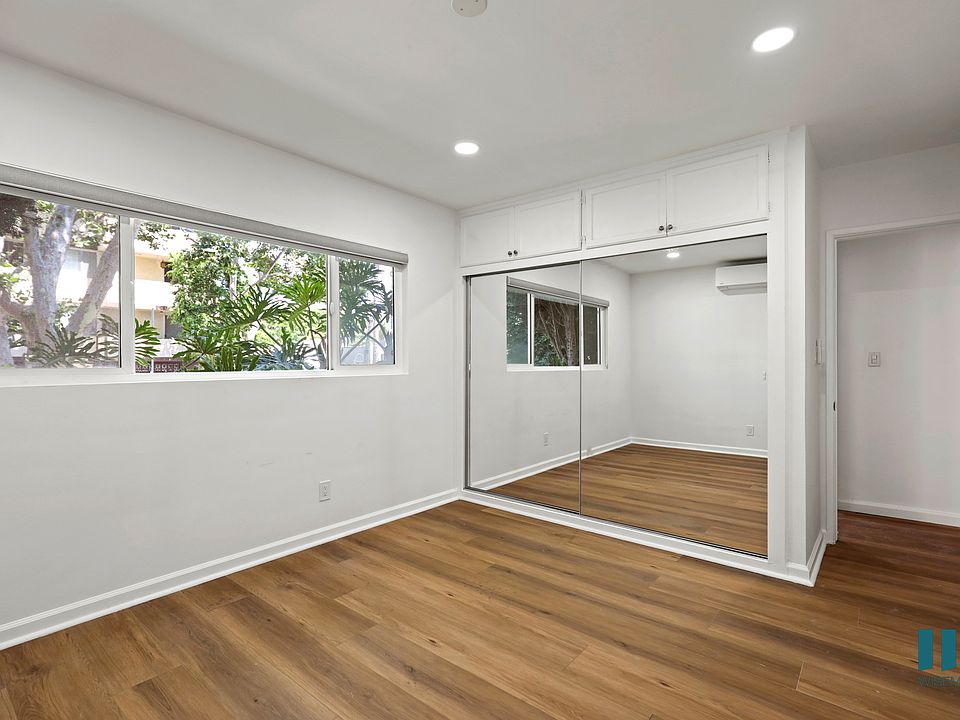 Bedroom with Windows, Mirrored Closet, Cabinet Storage, and Vinyl Flooring