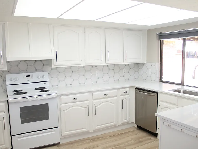 Renovated kitchen featuring a stylish backsplash, stove, dishwasher, and a large window that fills the space with beautiful natural light.