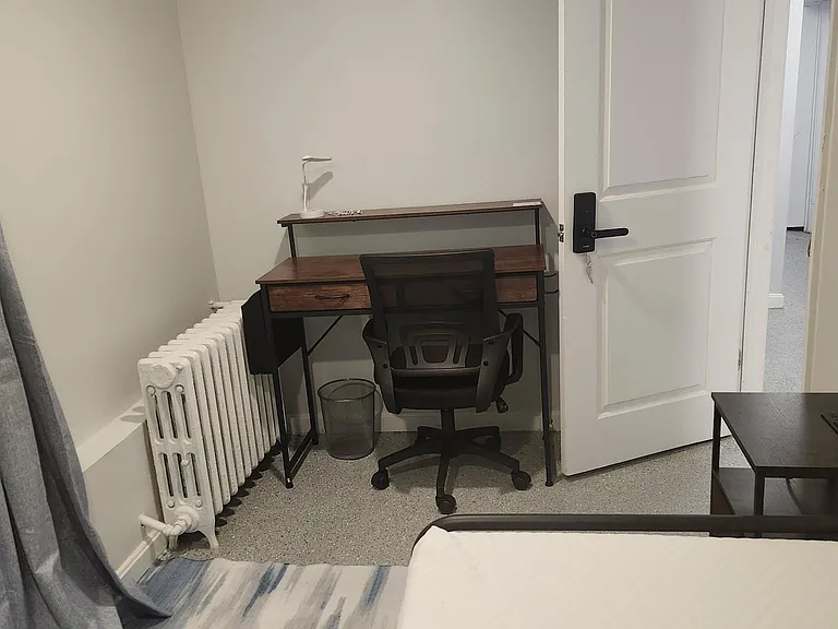 Private bedroom with a work desk setup, neutral finishes, and convenient access to the hallway.