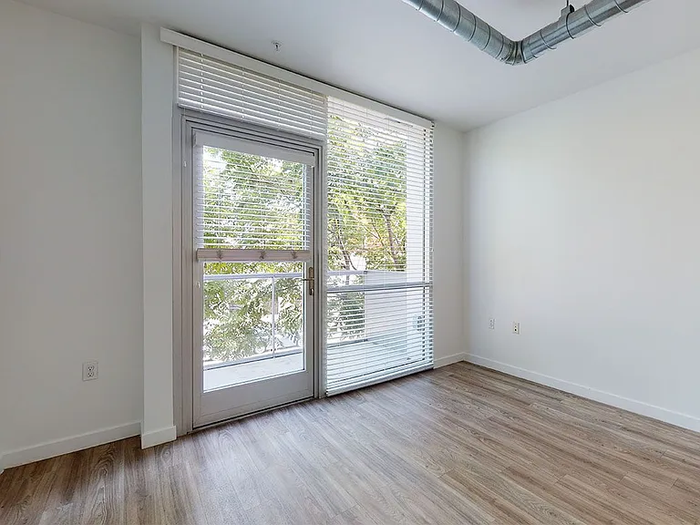 Apartment living room with wood-style flooring and floor-to-ceiling windows.