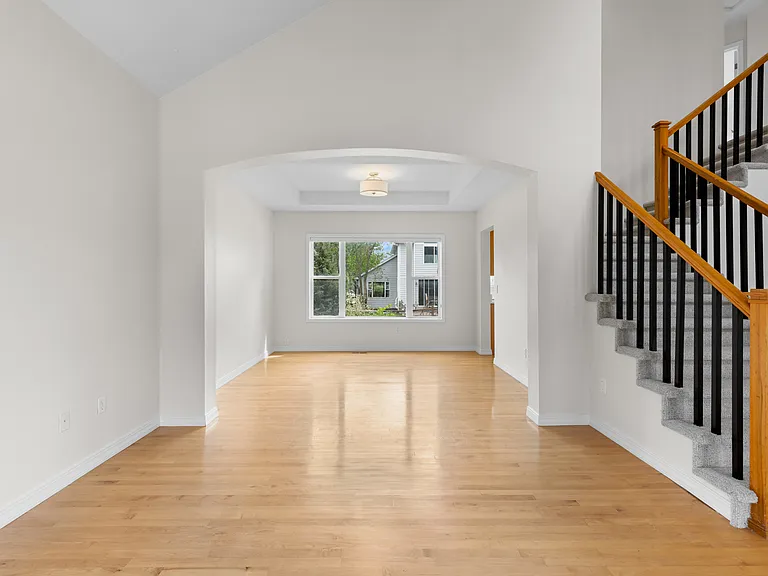 The arched opening, vaulted ceilings, and open sightlines help create a bright, airy flow between the front living/sitting and dining spaces while adding architectural character throughout the main level.