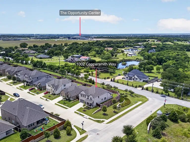 Aerial perspective of a suburban neighborhood featuring residential properties with manicured lawns and paved streets
